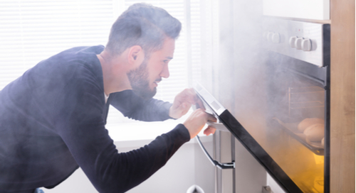 Guy watching smoke come out of the oven.