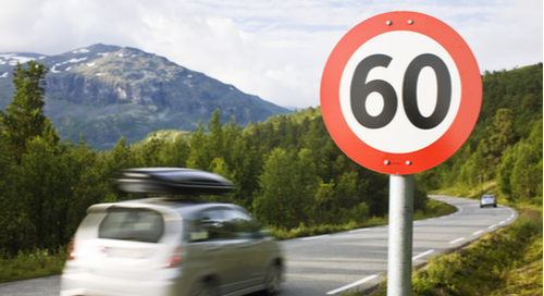 Car driving along highway next to speed sign