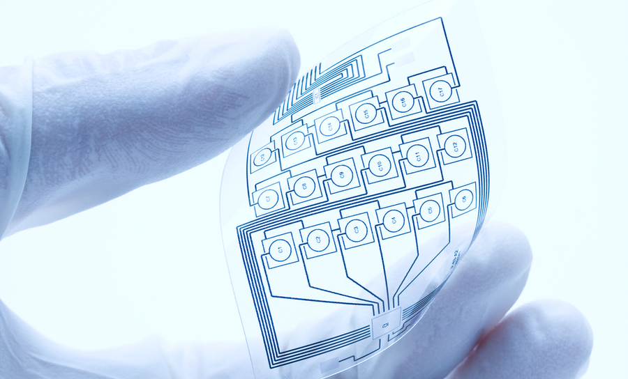 Gloved hand holding a flexible schematic of a circuit