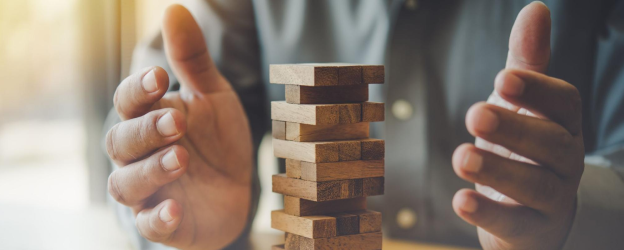 Hands around a tower of jenga blocks